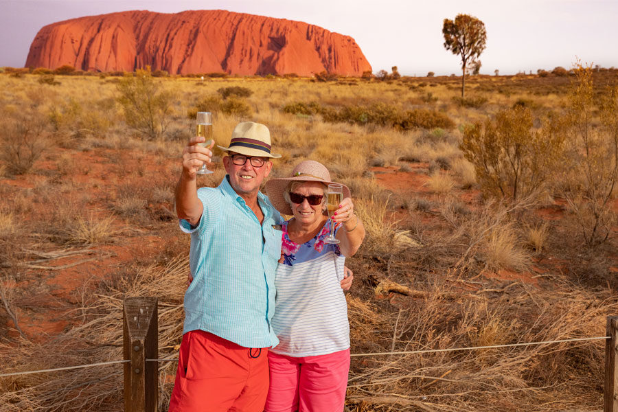 Couple enjoy a glass of sparkling wine during their Uluru tour operated by Emu Run Experience